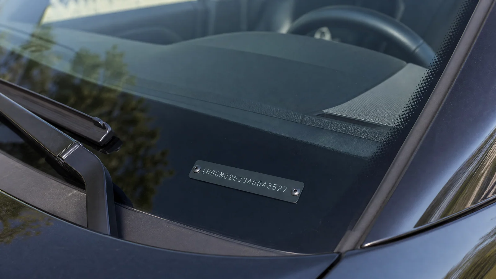 A VIN plate viewed through the windshield from outside the car